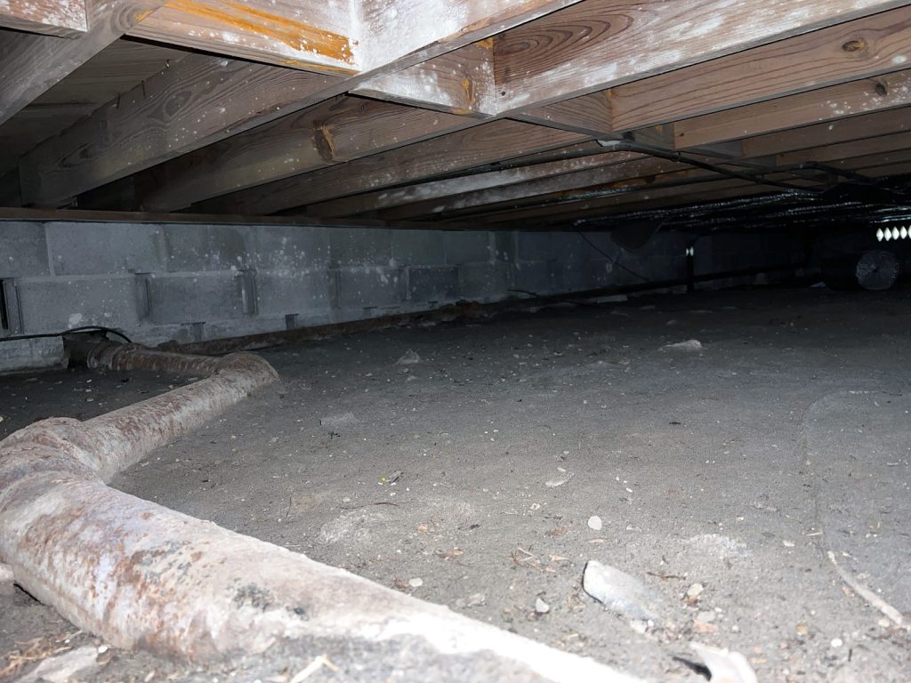 A dirty crawl space that is dark and not sealed.